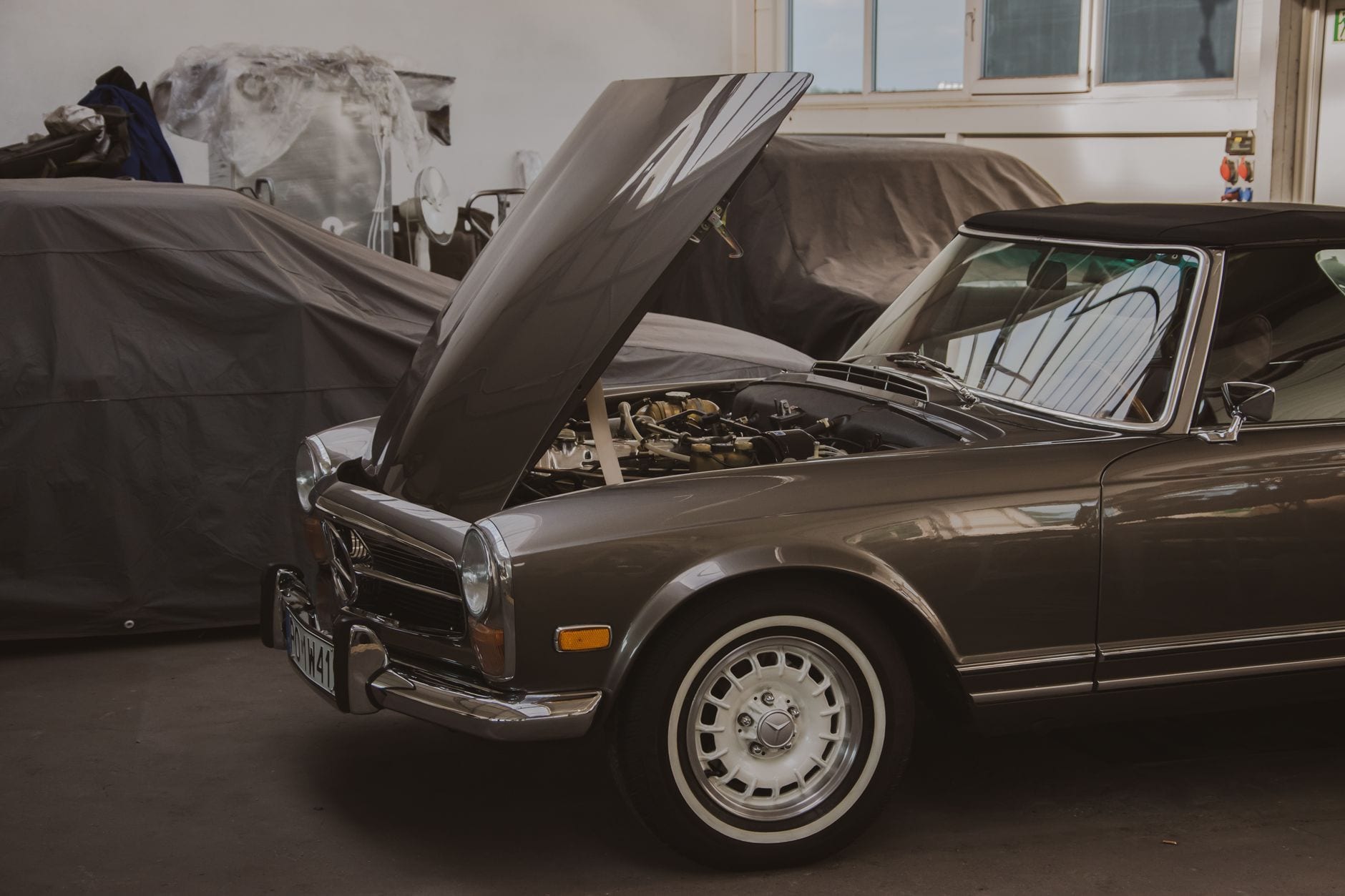 Classic convertible with the hood open in a repair garage